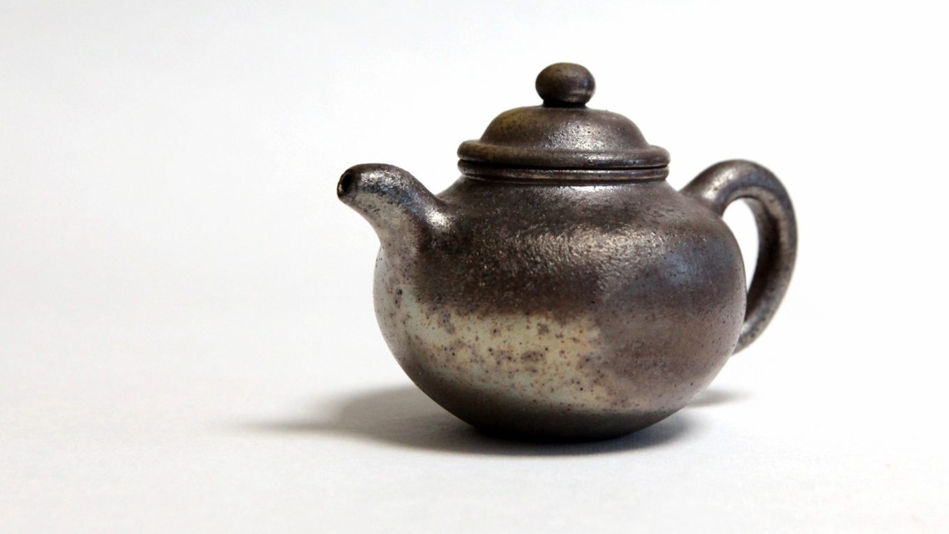 一道茶舍柴烧紫砂壶，圆腹短流，表面呈自然火痕